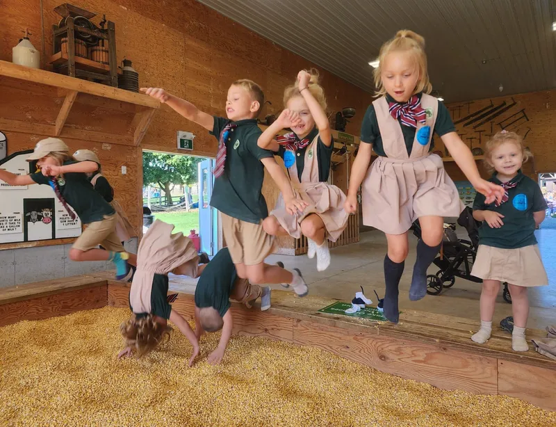 Children on farm field trip corn play demonstrating holistic outdoor learning at Alderwood Academy